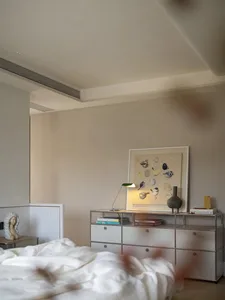 現代臥室內有大床、梳妝台、床頭櫃、燈具與花瓶，置於光線充足的空間
