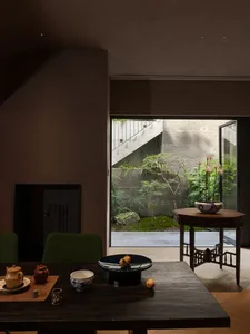 Cozy dining space with a wooden table and chairs, surrounded by potted plants and decorative vases