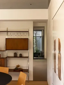 Modern kitchen dining space with a sink, dining table, chairs, and wine rack, featuring white walls and a well-organized atmosphere