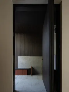 Dark hallway with a wooden wall and a small room with a bench, giving a simple and functional atmosphere