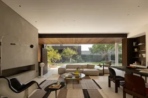 Modern living room with two couches, a dining table, chairs, and a fireplace, surrounded by natural light from a large window