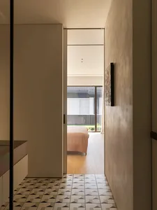 Cozy bedroom with a bed near the center, two chairs, and a couch, with natural light entering through a nearby window