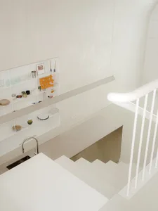 A well-organized kitchen with white walls and floors, featuring various objects and a sink, creating a functional living space