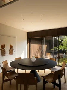Dining area with a round table and brown chairs, set in a well-designed living space for socializing and dining