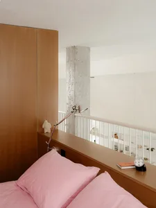 Cozy bedroom with a pink bedspread, a clock on a bedside table, and a warm atmosphere