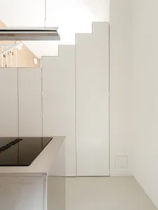 Modern kitchen with white walls and cabinets, featuring a stove top oven, refrigerator, and two sinks, with a focus on functionality and clean lines