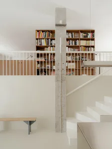 Residential interior with a wooden staircase, scattered books, and a warm atmosphere