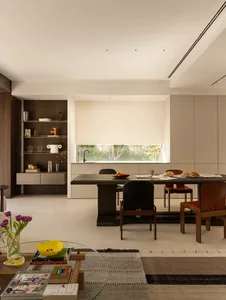 Modern kitchen and dining area with a large window, two chairs, a table, sink, refrigerator, and various decorative items