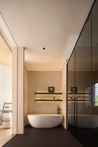 Modern bathroom with a large white marble bathtub, a mirror, and two bottles on the edge of the tub