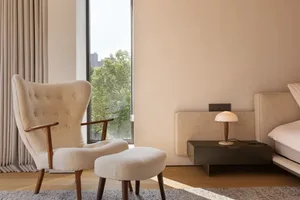 A well-lit living area with a white chair in front of a window, accompanied by a smaller chair in the background, creating a comfortable and inviting atmosphere