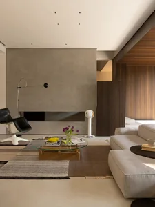 A modern living room with a couch, chair, dining table, vases, and books, creating a cozy atmosphere