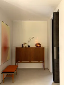 A cozy living space with a wooden cabinet, vases, and a potted plant, creating a warm and inviting atmosphere