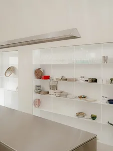 Well-organized kitchen with white walls and cabinets, displaying various items on the shelves in a neat and tidy manner
