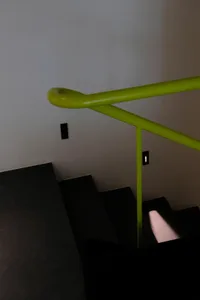 A photo of a staircase with a yellow handrail, set in a modern building with a residential or commercial atmosphere, featuring concrete or similar construction materials