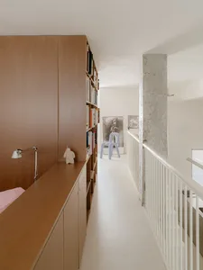 Open living area with wooden floors and cabinets, featuring a dining table, chairs, and books, creating a warm and inviting atmosphere