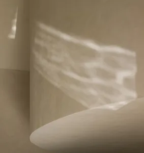 A calm interior space with a white wall, two windows, and interesting shadows created by sunlight
