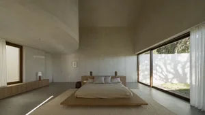 Open living area with a wooden bed and sofa, surrounded by neutral tones and clean lines, with a chair and nightstands adding to the cozy atmosphere