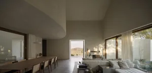Modern open concept living space with a large couch, dining table, chairs, fireplace, and rug, featuring a contemporary and inviting atmosphere