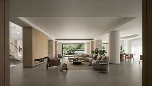 Bright and inviting living area with white interior, two couches, a chair, dining table, and potted plants