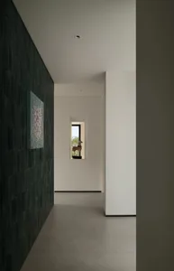 A clean and well-lit interior hallway with white walls and a tile floor, featuring two windows on either side