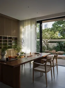 Cozy dining space with a wooden table, three chairs, and two potted plants, creating a warm and inviting atmosphere