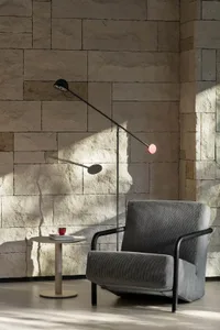 A gray chair sits in front of a stone wall, accompanied by a dining table and two cups on nearby surfaces, creating a calm and inviting atmosphere