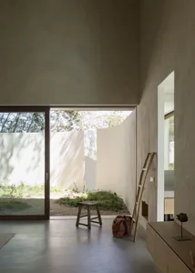 A small, well-organized room with a white color scheme, a table, two chairs, and a window allowing natural light to enter