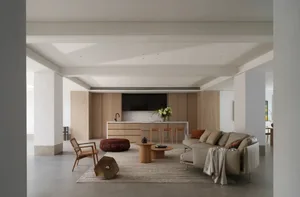 Open living space with white walls, wooden floors, two couches, a chair, a sink, a refrigerator, and a potted plant