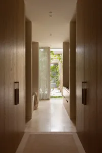 A bright and inviting hallway with a white tile floor, large window, and two doors leading to a living area