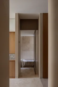 A warm and inviting hallway with wooden features, white walls, and two doorways leading to adjacent rooms