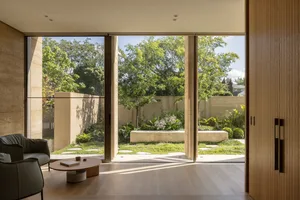 Open living area with large windows, glass doors, and a bench, featuring a modern and contemporary design with clean lines and minimalistic elements