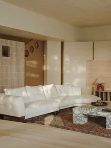 Bright and inviting living area with white couches, a coffee table, and sunlight streaming through the windows
