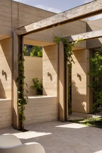 A modern building with a concrete exterior, featuring several windows, two archways, and natural light from the daytime sun