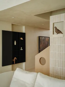 A well-lit living area in a coastal villa with a white couch, birds perched on surfaces, and decorative vases, creating a comfortable and inviting atmosphere