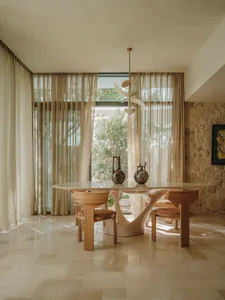 Cozy dining space with a wooden table and chairs, surrounded by curtains that allow natural light and maintain privacy
