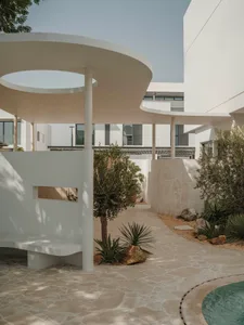 A modern coastal villa with a central roundabout, white exterior, and ample natural light from various windows