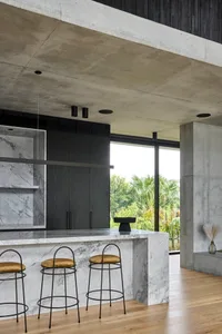 Modern kitchen with black and white theme, large island, stools, chairs, and sliding glass door to living area