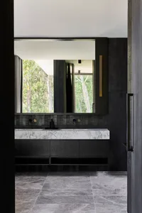 Bathroom with modern black cabinets, double sinks, and a window with a view of trees outside