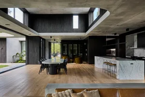Open living area with wooden floors and walls, a dining table, chairs, and a couch, creating a warm and inviting atmosphere