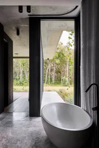 A calm bathroom with a white bathtub, two potted plants, and a sink, lit by natural light from a window