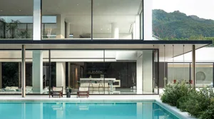 A relaxing pool area with natural light pouring in through large windows, surrounded by chairs and decorative bottles