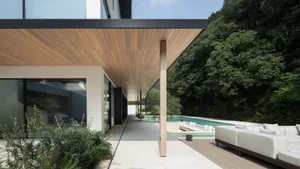 A relaxing outdoor living area with a swimming pool surrounded by a patio, featuring two chairs and a couch
