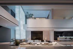 Open living area with a white couch, hardwood floor, chairs, potted plants, and decorative bottles, creating a clean and inviting atmosphere