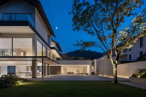 A modern living area with a dining table and chairs, a couch, and a cozy atmosphere at night