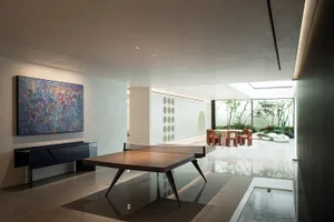 A modern dining space with a large wooden table surrounded by chairs, a pool table, and well-lit, creating a comfortable atmosphere