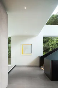 Bright open living area with a large window, two staircases, and a painting on the wall