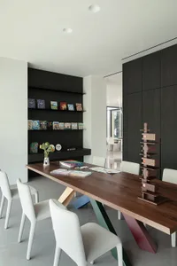 A cozy living area with a wooden dining table, chairs, and a bookshelf, surrounded by books and creating a warm atmosphere