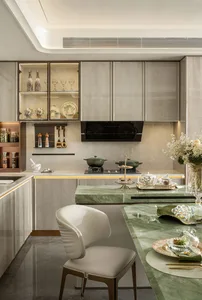 Modern kitchen with white cabinets, gray countertops, and a black stove, featuring wine glasses and a clean contemporary design