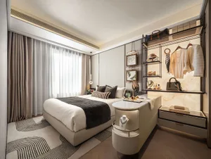 Well-lit bedroom with a white couch, a large window, and a sink, featuring two beds, a clock, and various personal items