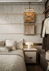 A modern bedroom with a bed, dresser, and artwork on the walls, featuring neutral tones and good lighting